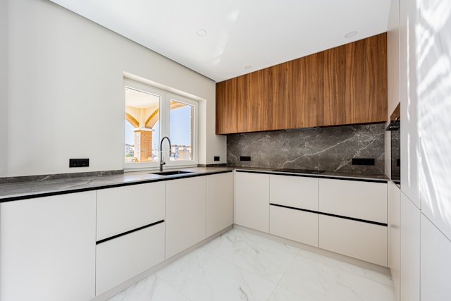 Modern L-shaped kitchen with white cabinets and wood details.